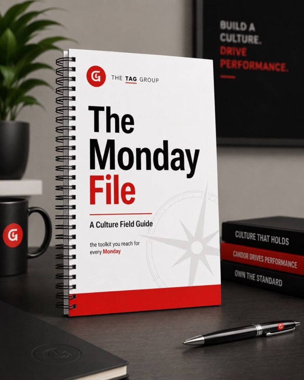 The Monday File, a spiral-bound culture field guide from The TAG Group, standing on a desk beside a branded mug and pen.